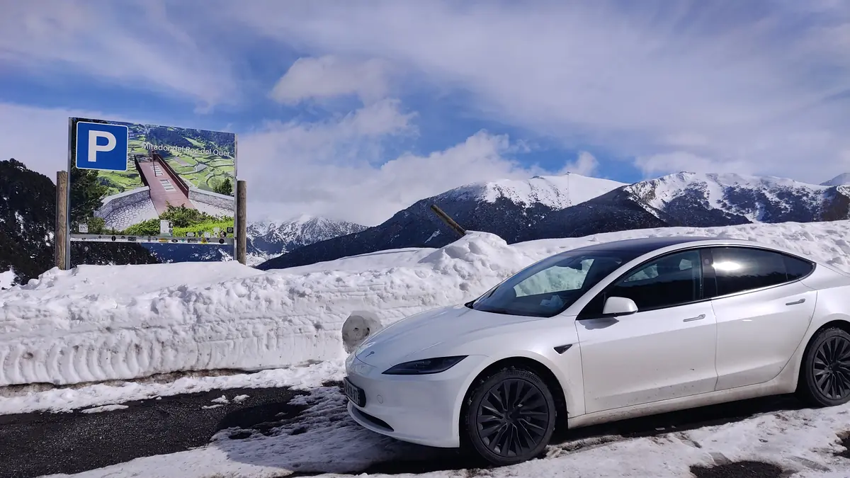 La Tesla Model 3 d’Aude VTC sur la neige en Andorre, chaîne des Pyrénées enneigée derrière.