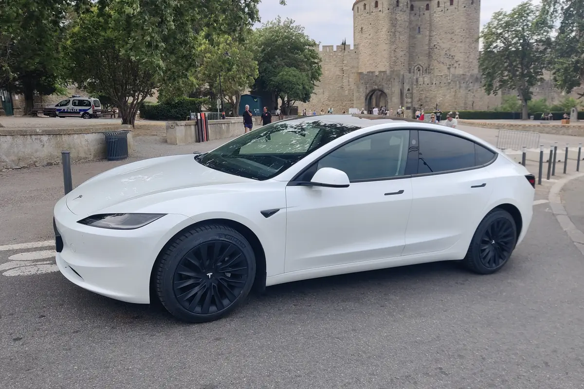La Tesla Model 3 blanche d’Aude VTC devant les remparts de la Cité de Carcassonne, première des huit forteresses inscrites à l’UNESCO.