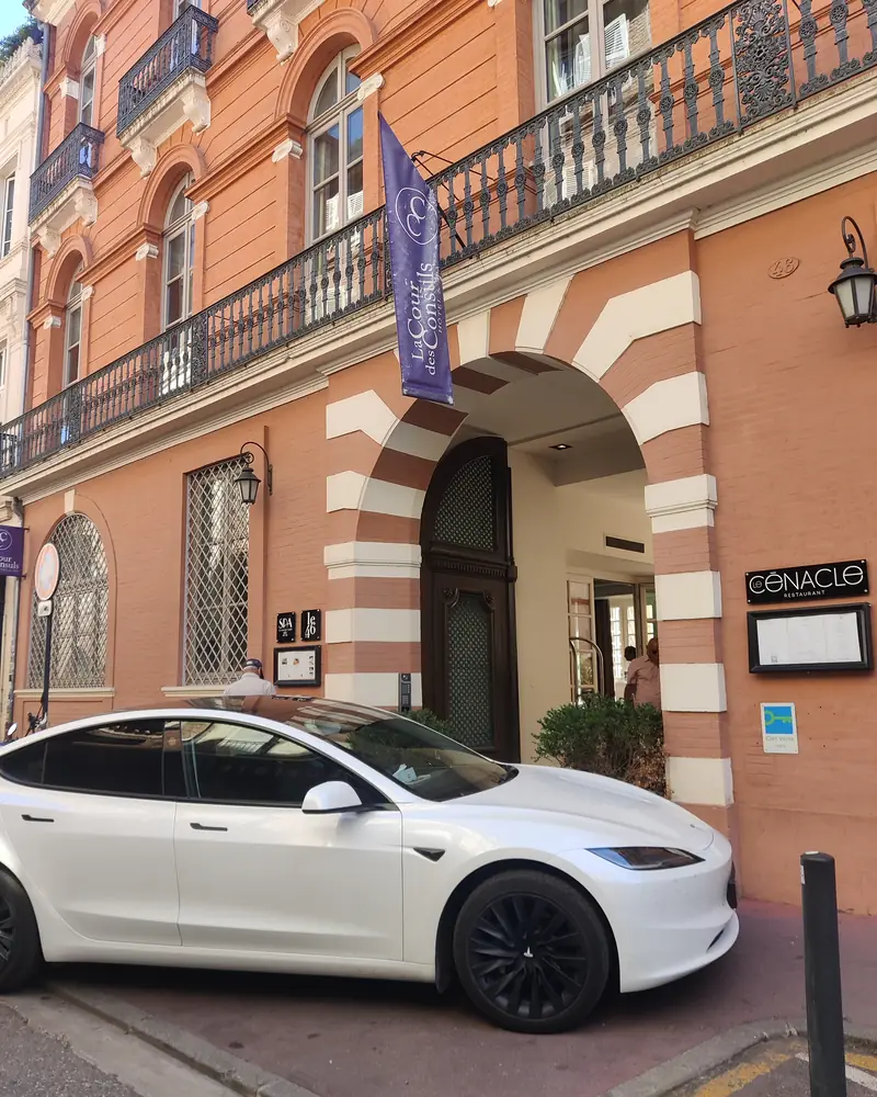 La Tesla Model 3 d’Aude VTC devant l’entrée d’un hôtel de la brique rose toulousaine.