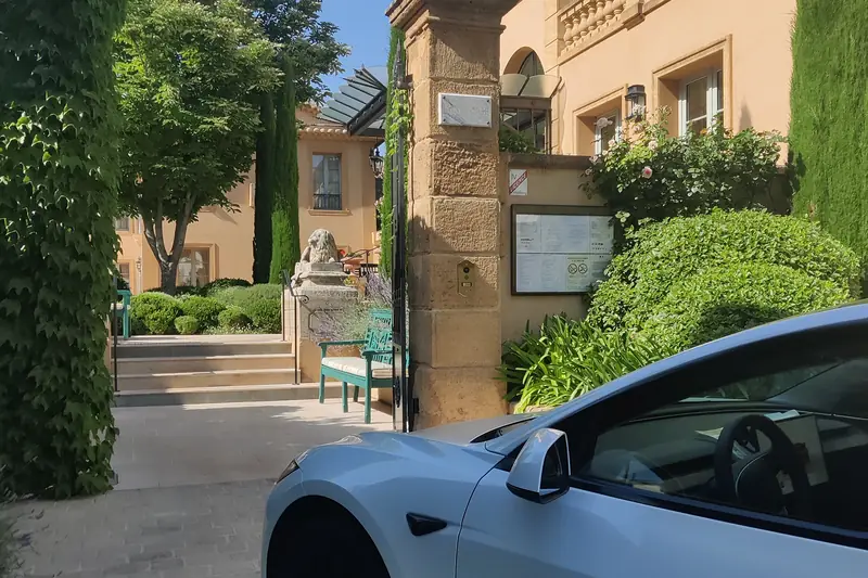 La Tesla Model 3 blanche d’Aude VTC devant l’entrée d’un domaine de réception, près de Carcassonne.