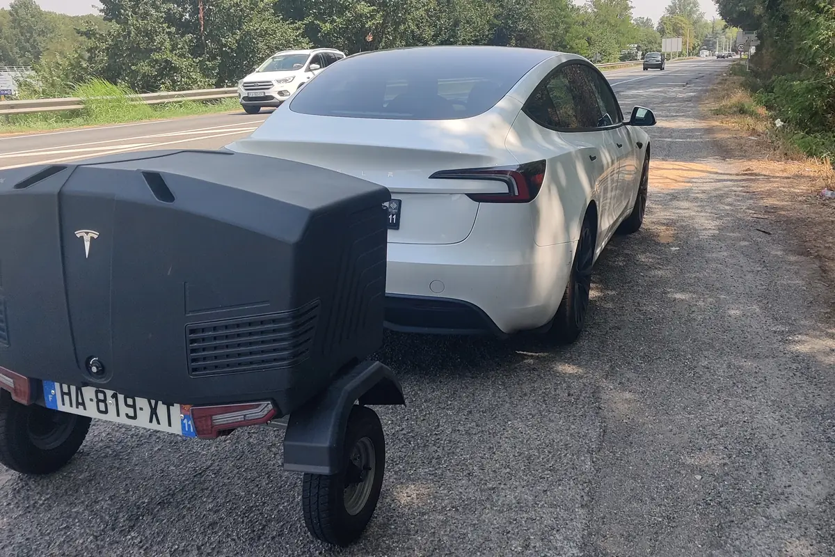 La remorque à bagages TowBox attelée à la Tesla Model 3 d’Aude VTC, au bord d’une route de l’Aude.