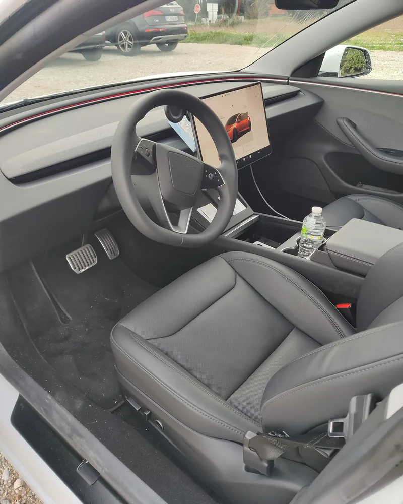 Poste de conduite de la Tesla Model 3 : volant, écran central et sièges avant.