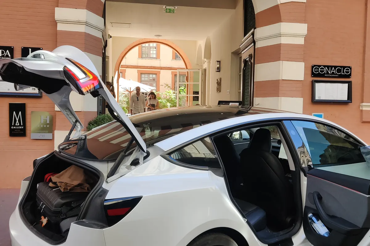 La Tesla Model 3 d’Aude VTC, coffre ouvert, devant un hôtel de la brique rose toulousaine.